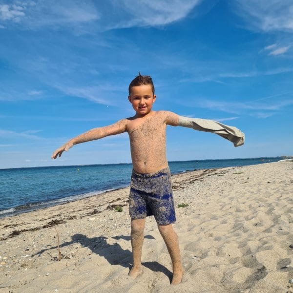 Grå arm dreng i sandet